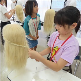 マネキンの髪を三つ編みにする様子