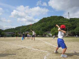 ソフトボール投げは、赤い旗の向こうの山をめざします。