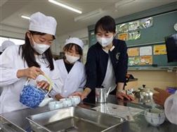 湯飲みに白湯を注ぐ児童