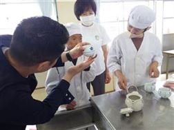 湯飲みの持ち方を学ぶ児童