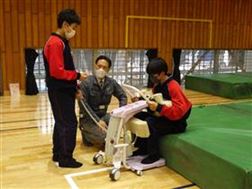 説明を受けながら機械操作をする生徒
