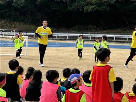 サッカーする選手と子ども