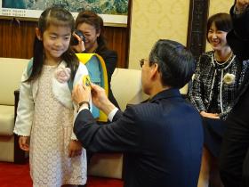 安田教育長から黄色いワッペンをつけてもらう新一年生代表児童