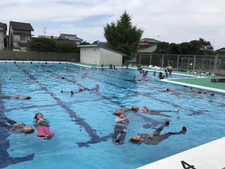 衣類を着たままプールに入り、水に浮く練習をする子ども2